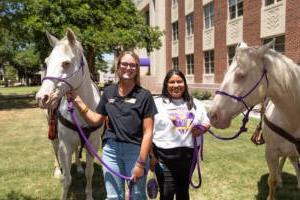 Student worker Sayler Beerwinkle poses with her supervisor, Sarah Palma '22/'24, after gathering content for a social media post.